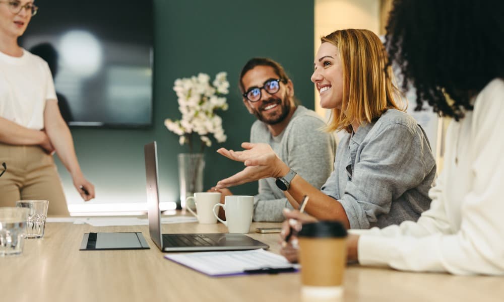 A diverse group of smiling people having a discussion around a conference table.