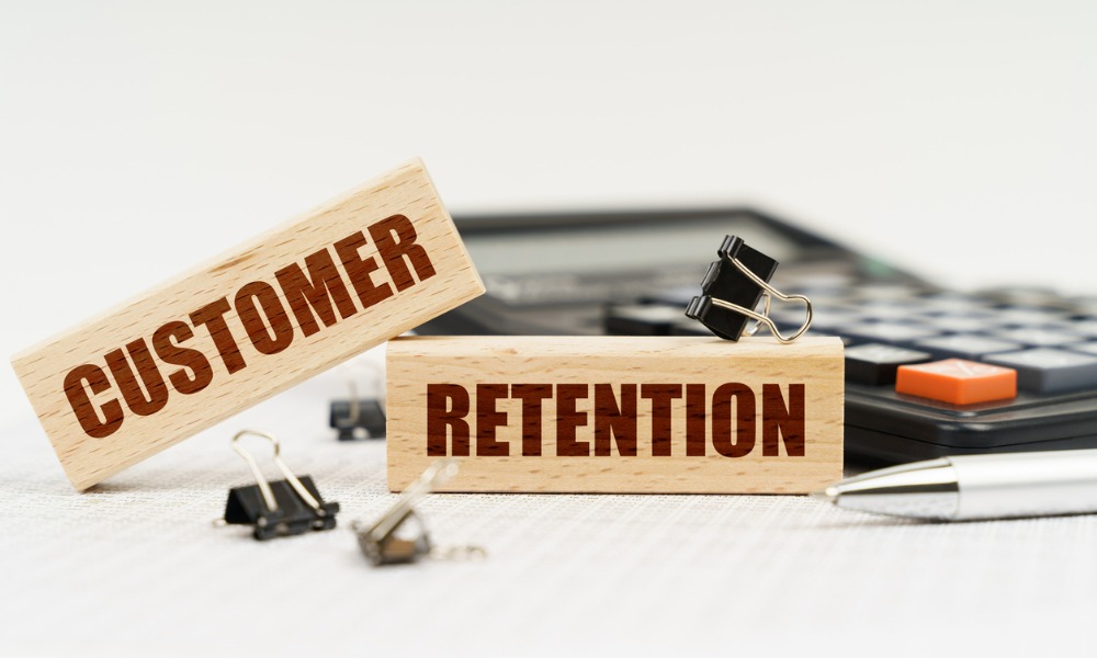 A white background with a calculator, pen, reports, and wooden blocks labeled “customer retention”