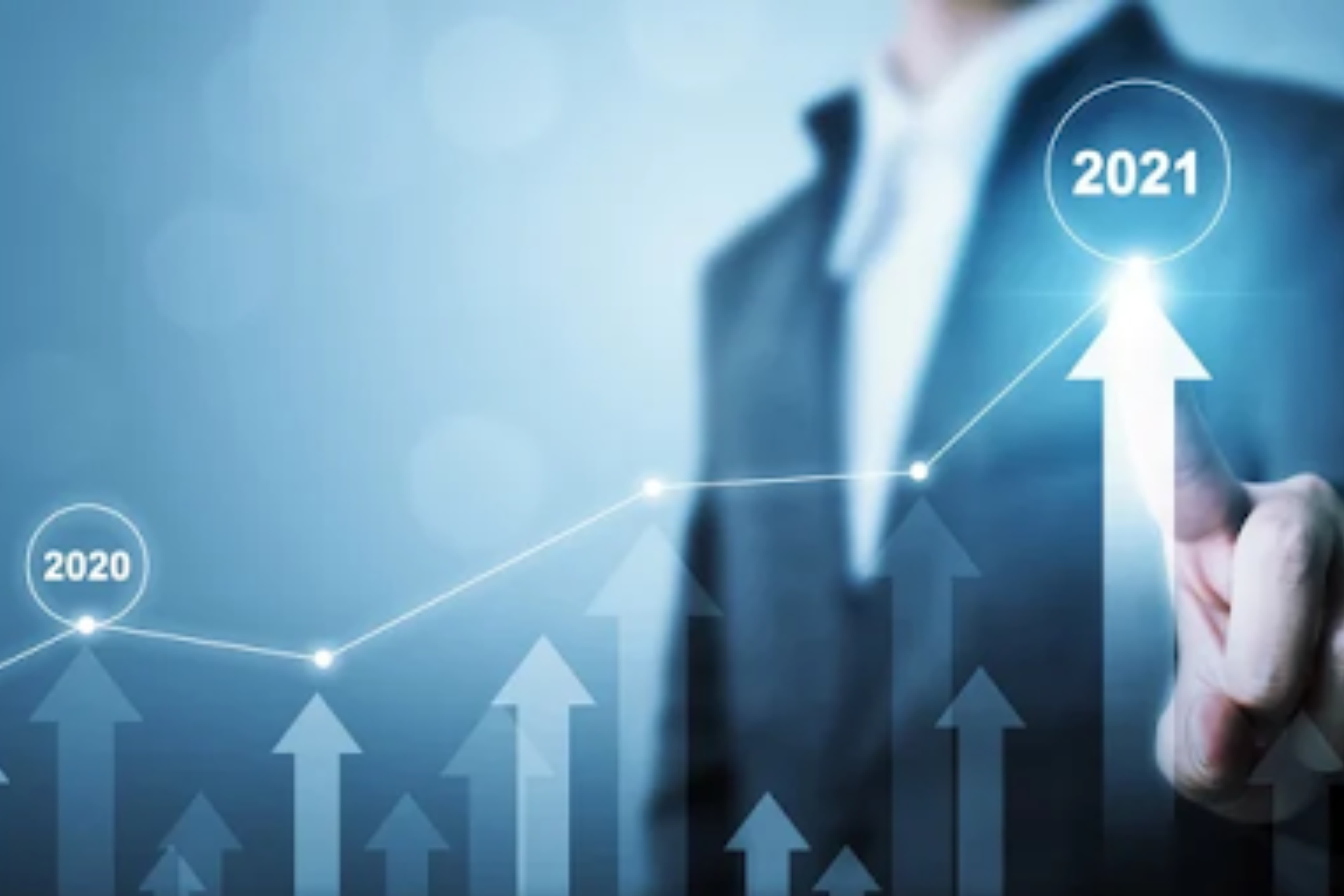 A person in a suit points at an upward-trending graph, transitioning from 2020 to 2021, symbolizing growth and success.