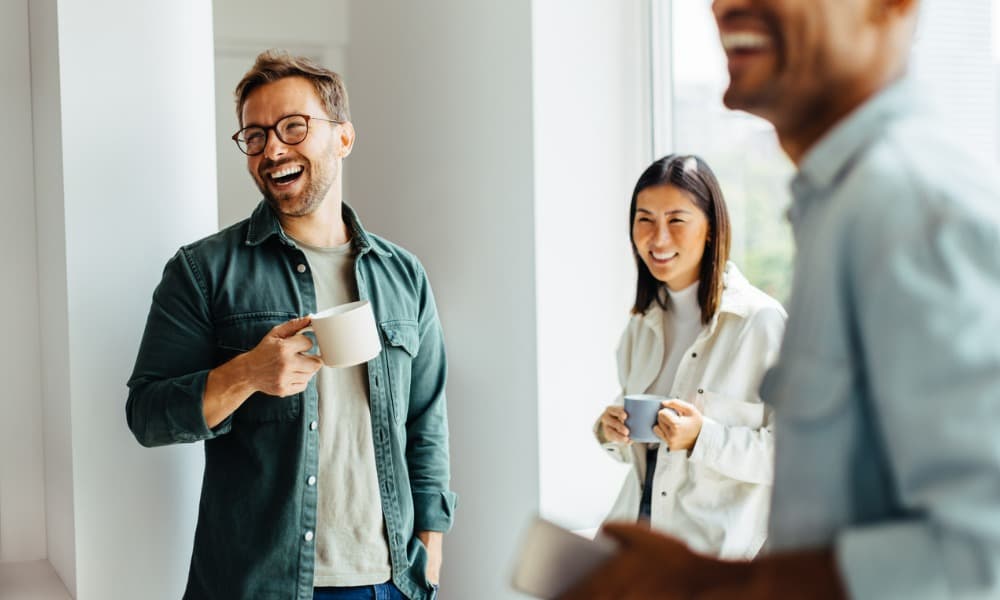 A group of happy, laughing businesspeople taking a coffee break at work 