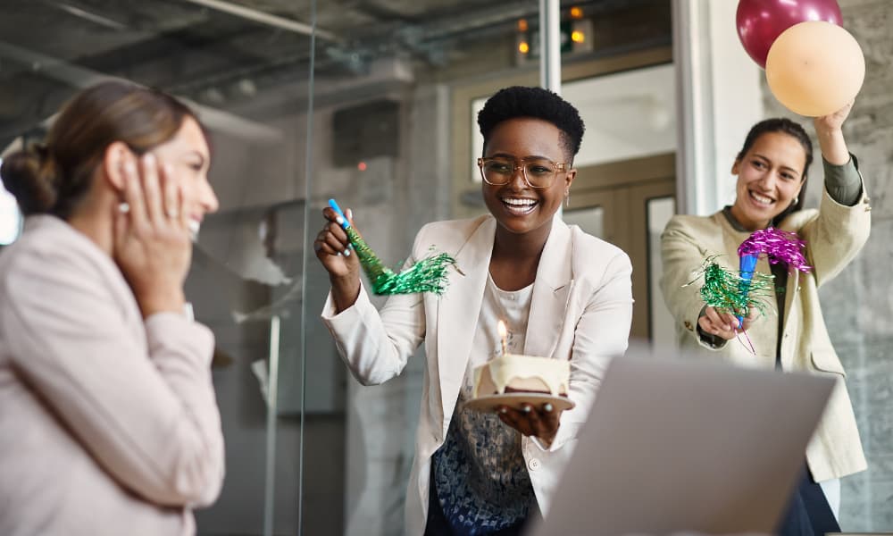 Cheerful female entrepreneurs throwing a surprise party for their colleague's Birthday in the office.
