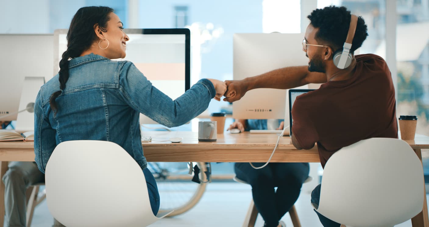 Two happy workers fist-bump to celebrate their success in an employee rewards program and the instant gratification of prize automation.