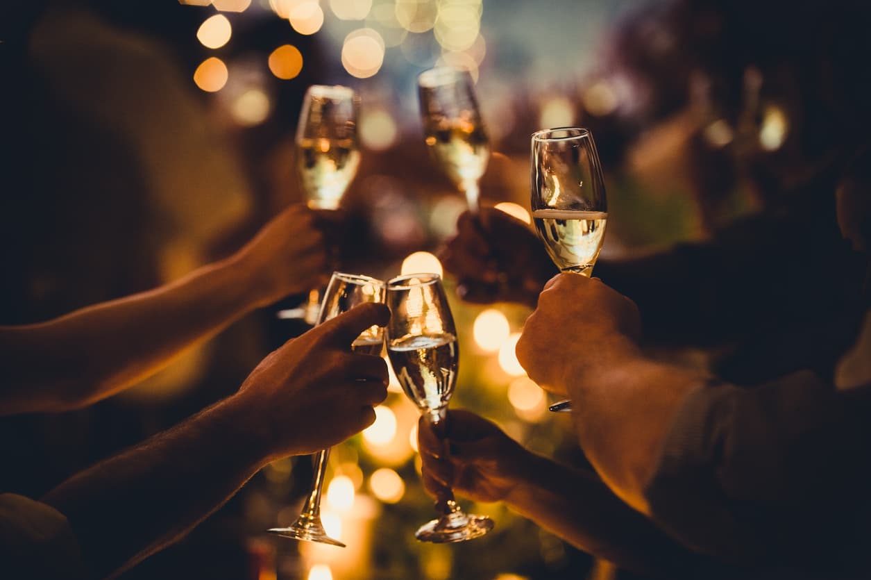 Five employees making a toast with their champagne glasses during a company holiday party.