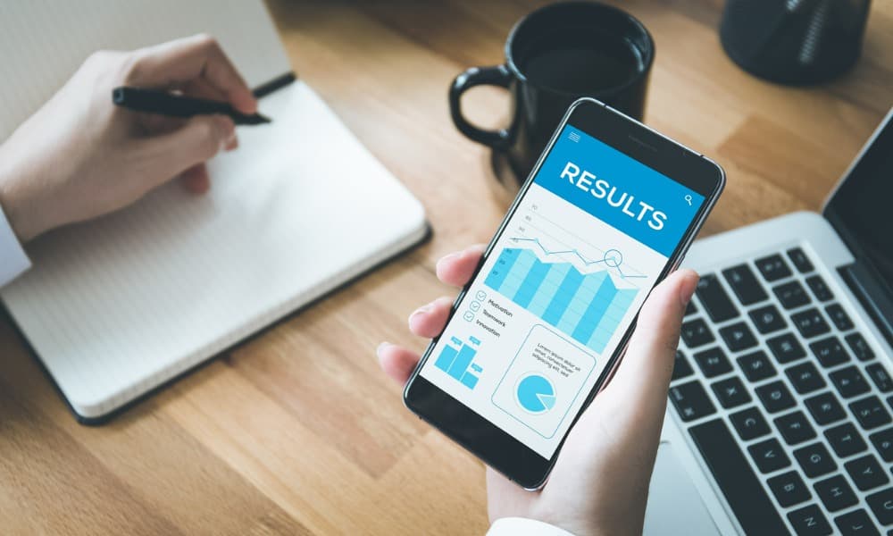 A man holding a phone displaying a graph of results.