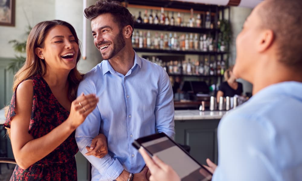 Two customers smile as an employee asks them for their feedback to ensure customer success and customer happiness