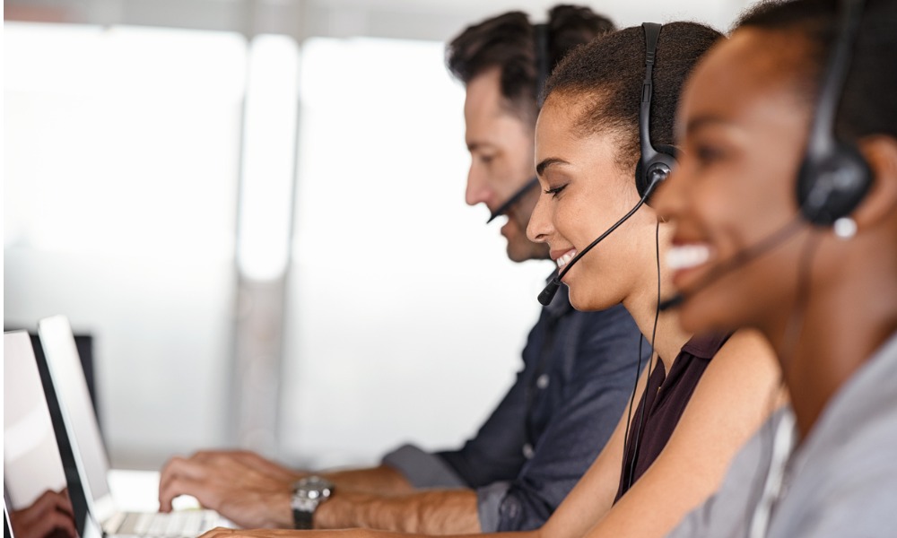 Customer service personnel smiling and talking on headsets.