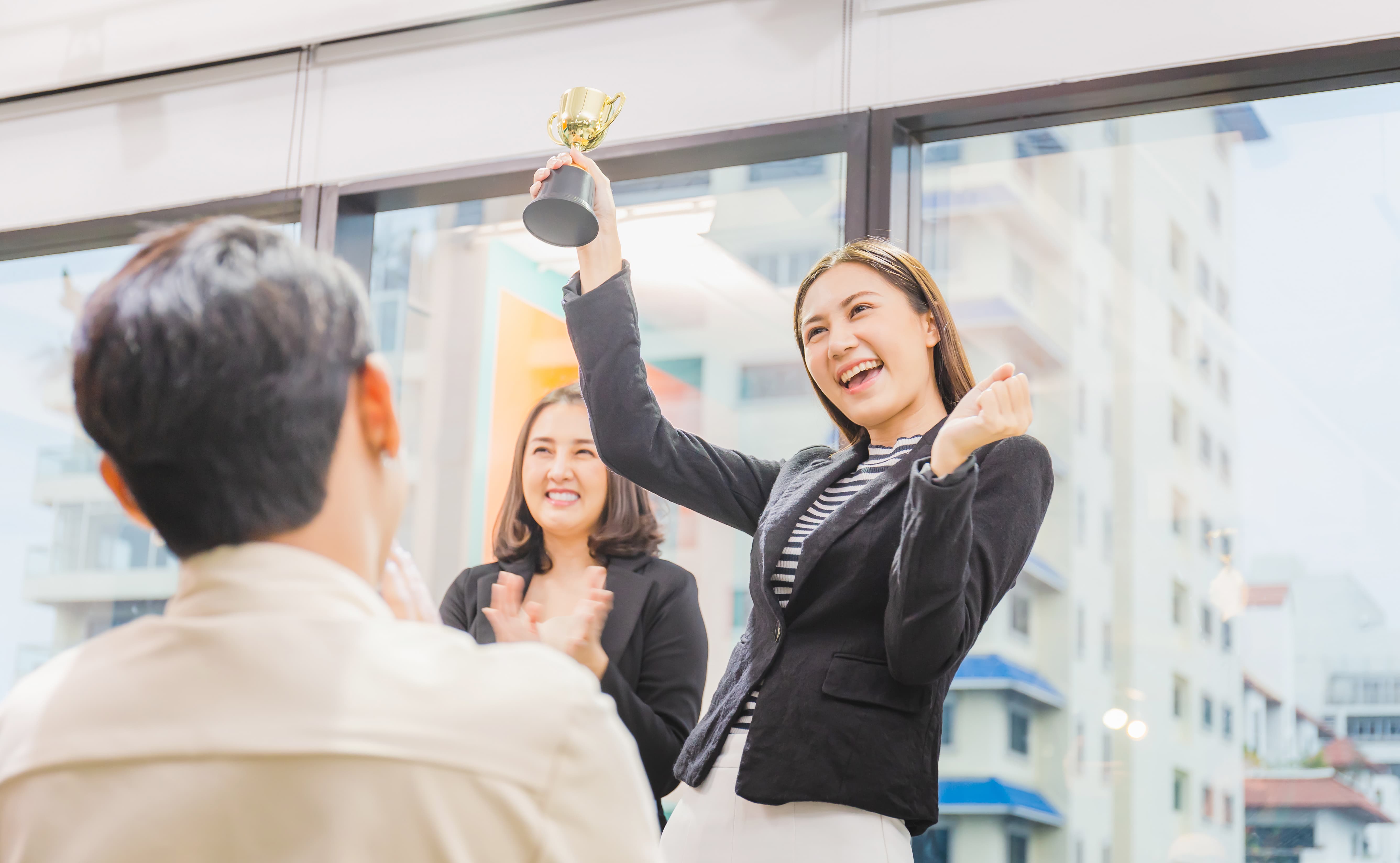 Business woman holding award trophy at meeting room