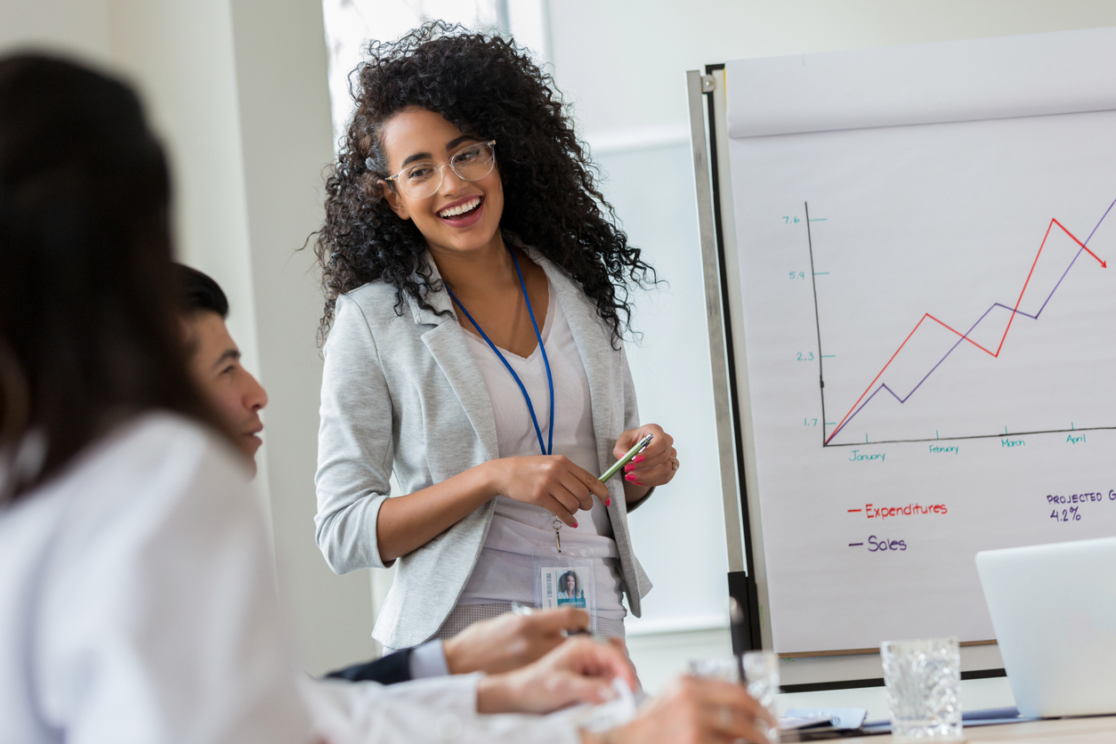 saleswoman smiling at colleagues looking at a sales graph