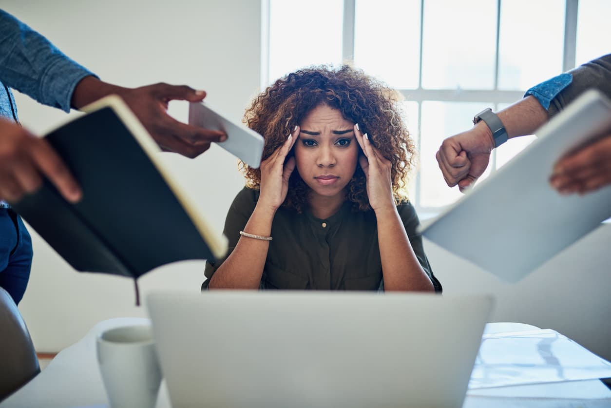 A manager suffering from burnout as several employees demand her attention at work.