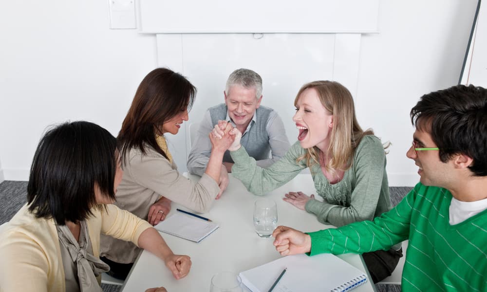 A team arm wrestles because of their better camaraderie due to gamification in the workplace