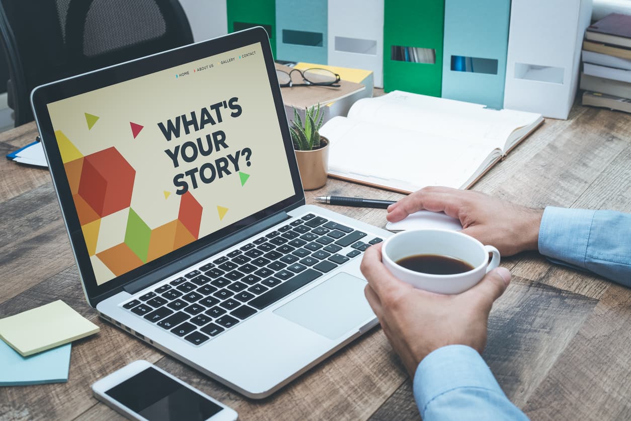 person holding coffee looking at laptop that says what’s your story