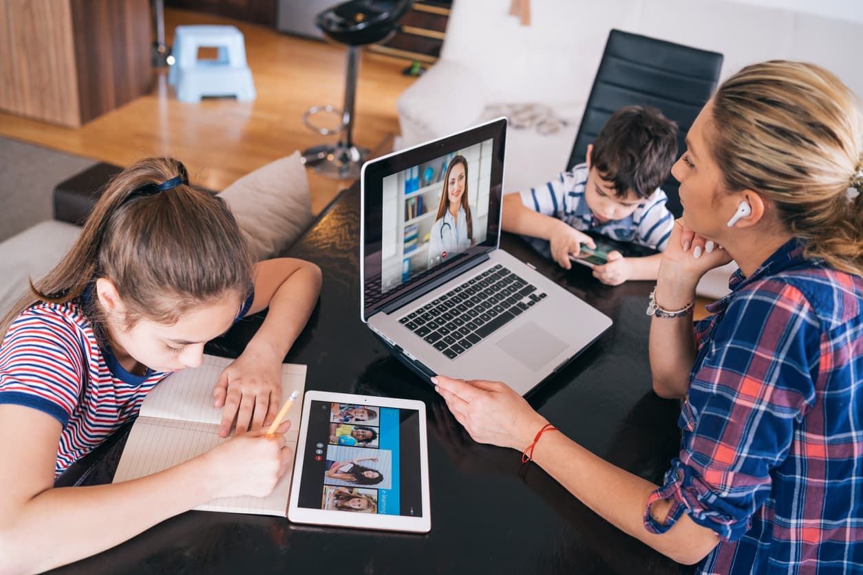 Remote worker at work while having to keep an eye on her daughter and son at home at the same time.