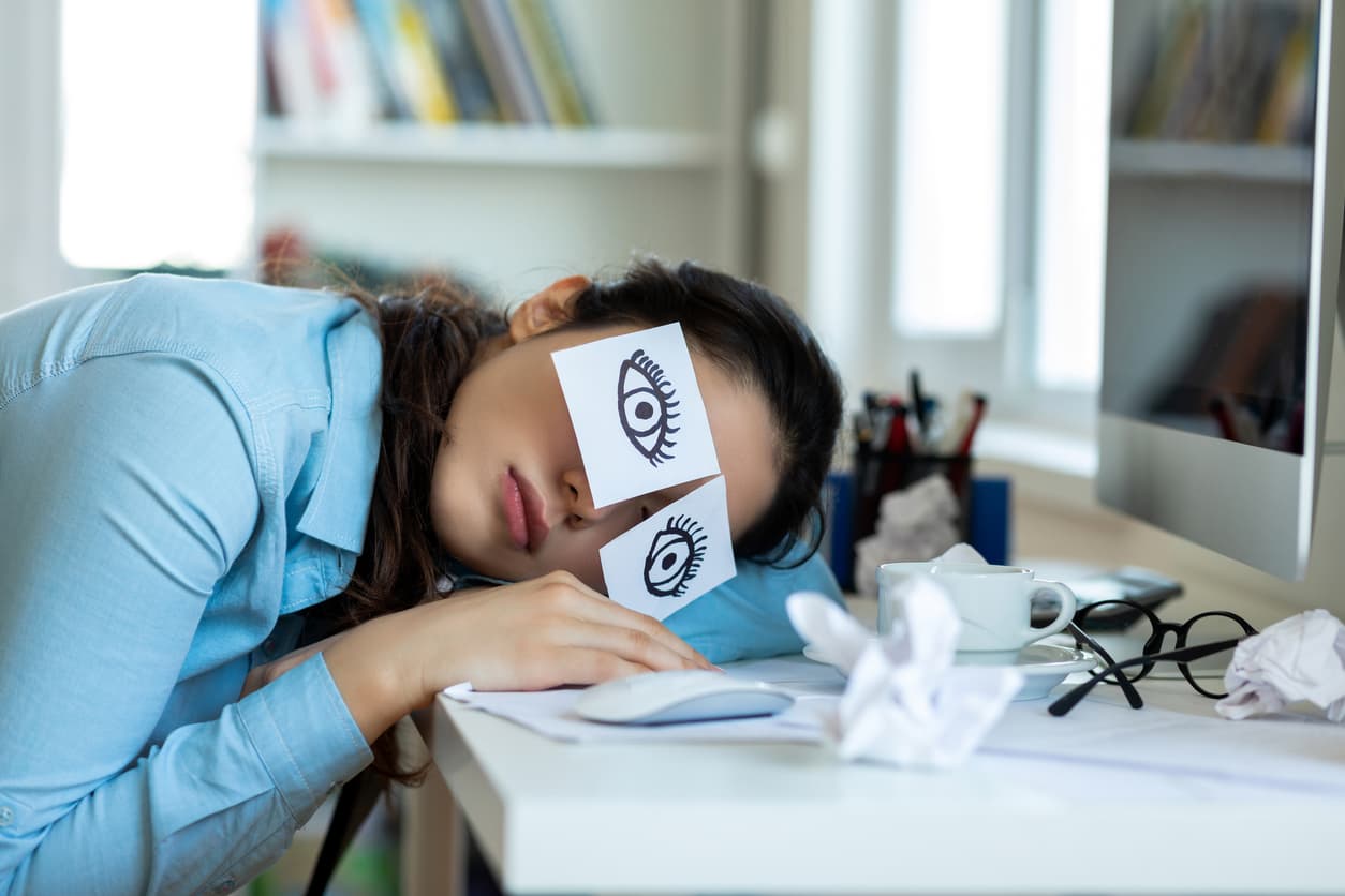 A salesperson suffering from burnout and finding it hard to stay awake at the office.