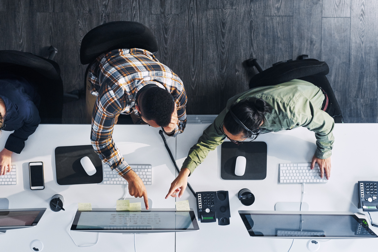 overhead view of two help desk workers reviewing ticketing metrics on a computer