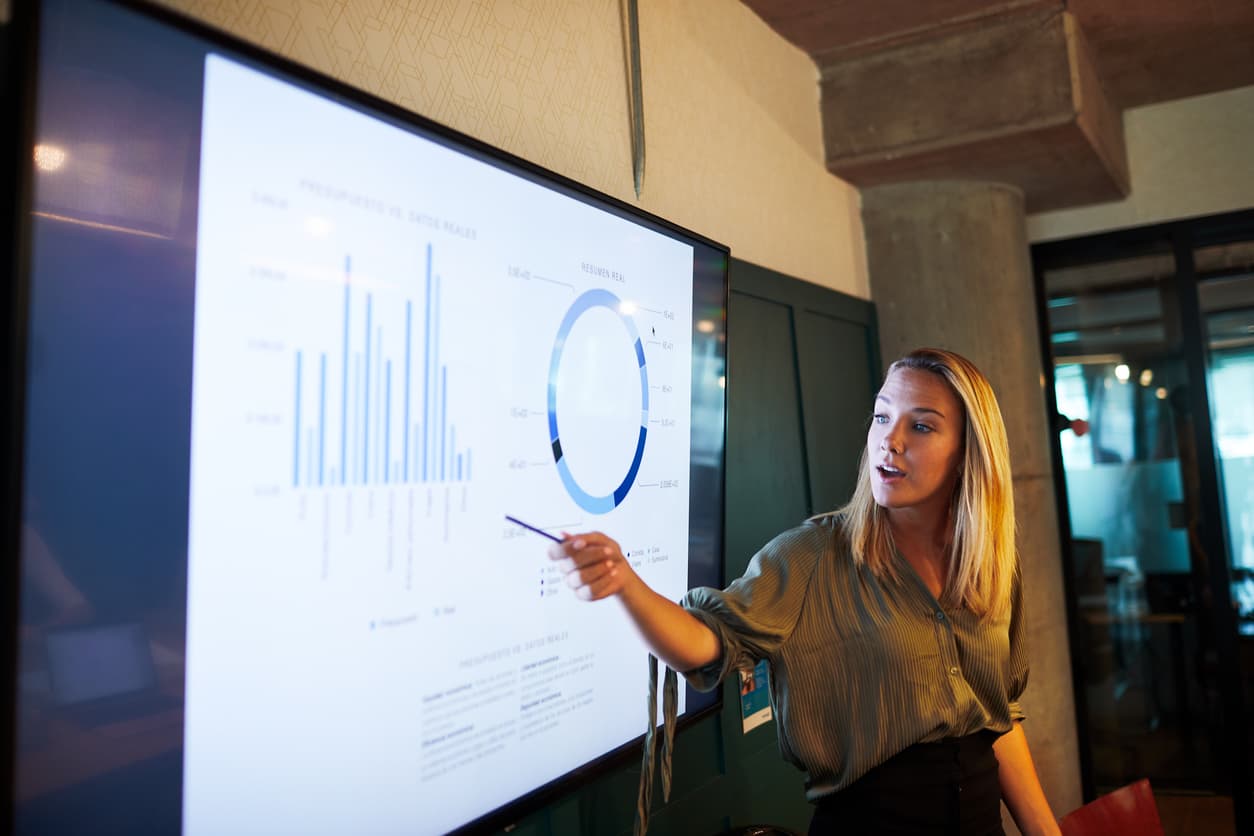 Woman pointing to a lit screen of help desk metrics