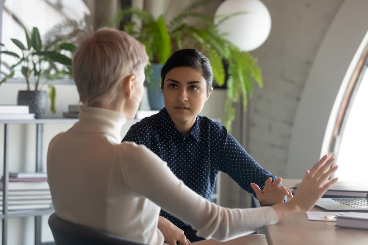 Team leader having a talk with an unengaged employee at a table.